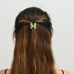 Gros plan d'une mini pince à cheveux géométrique vert clair portée sur modèle