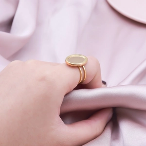 Detail of golden stainless steel ring with textured round plate and double band on satin