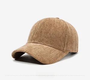 Detail shot of the brown herringbone pattern fabric and curved brim of the baseball cap