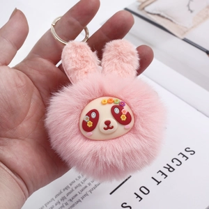 Close-up of pink plush bunny keychain with soft fur, cute floral face and golden ring