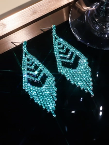 Detailed macro view of luxurious blue rhinestone tassel earrings with a triangular design