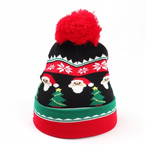 Detail of winter knit hat with red pompom, Santa Claus motifs and snowflake patterns
