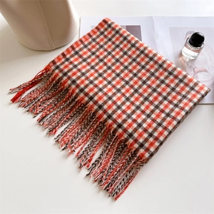 Detail of red and white plaid scarf with fringe tassels and woven cashmere texture