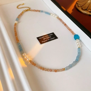 Detail of square aquamarine and pearl beaded necklace with 925 silver tag on jewelry tray