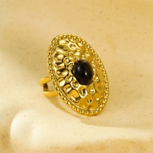 Macro view of vintage gold oval ring with hammered texture and black natural stone