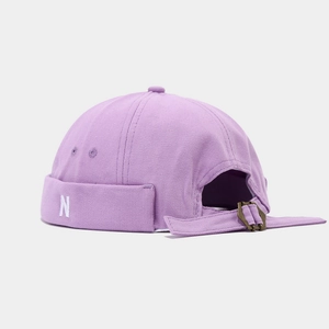 Detail of light purple canvas skullcap featuring white N embroidery and bronze buckle