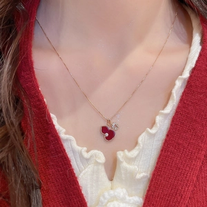 Close-up of gold calabash pendant necklace with red enamel and zircon coin charm