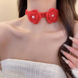Detail of red crochet floral choker necklace with pearl center and soft knitted texture