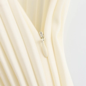 Elegant beige two-piece set featuring close-up of a high-quality invisible zipper and pleated fabric
