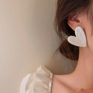 Elegant white heart-shaped resin earrings with marble texture on a female model