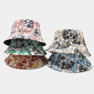 Close-up of reversible bucket hats with vibrant floral and leaf patterns in five colorways