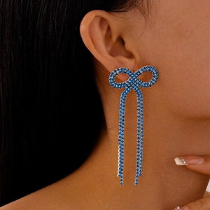 Gros plan de boucles d'oreilles nœuds strass bleu roi avec longues franges
