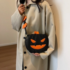 Crossbody Halloween pumpkin bag in black leather featuring an orange evil smile and bat strap