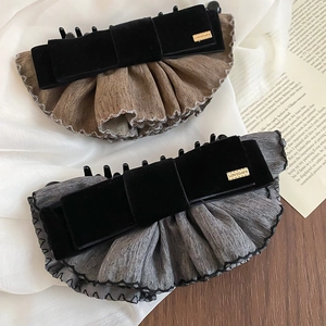 Détail de barrettes à nœud en velours avec tissu plissé et plaque dorée gravée