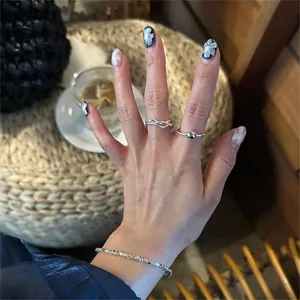 Detail of 925 sterling silver twist ring and beaded bracelet worn on hand in natural light