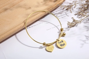 Detailopname van gouden roestvrijstalen verstelbare armband met Love-hangers