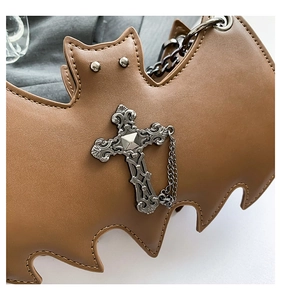 Macro detail of gothic bat bag featuring brown faux leather texture and silver cross charm