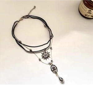 Detail of layered bohemian necklace with black cord, silver chains and crystal star pendant