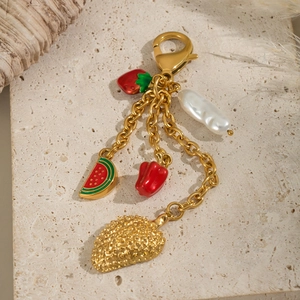 Détail de porte-clés avec pendentifs fraise, pastèque et perle sur fond pierre beige