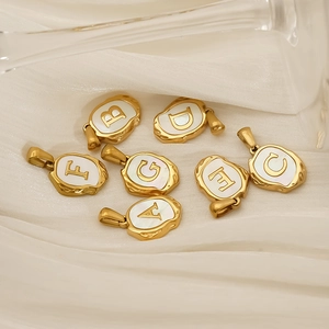 Golden titanium steel alphabet pendants with white shell inlay on white silk fabric