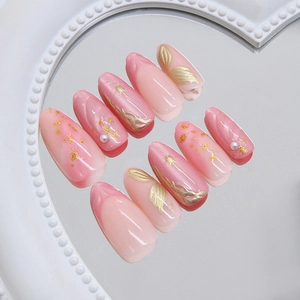 Pink ombre press-on nails with gold starburst relief and pearls on a mirror tray