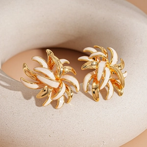 18K gold plated flower stud earrings with white enamel finish on a beige stand