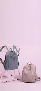 Detail view of pink and grey nylon backpacks with multiple zipper pockets and logo