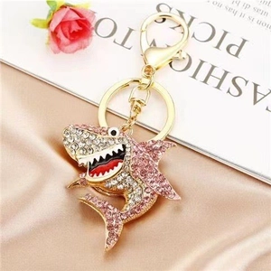 Macro shot of shark keychain with pink crystals on champagne silk background