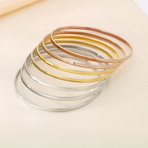 Detailed view of stacked minimalist slim titanium steel bangles in gold silver rose gold
