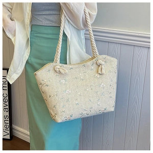 Détail du sac cabas beige en paille avec broderie florale et poignées en corde