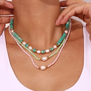 Close-up of triple-layered necklace with turquoise, green, and pink beads with freshwater pearls