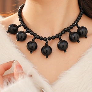 Close-up of black beaded necklace with large spherical pendants on female model