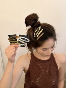 Close-up of elegant acetate hair clips and wavy metal pins on a black display card