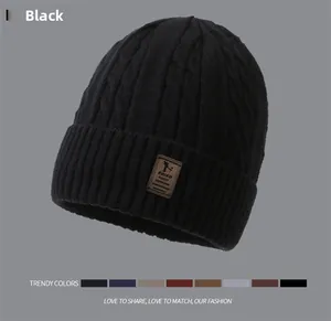 Close-up of black cable knit beanie texture with a premium brown faux leather patch detail
