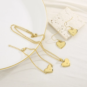 Détails d'une parure dorée en forme de cœur avec collier et boucles sur pierre