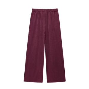 Detail view of burgundy wide-leg trousers featuring a flexible elastic high waistband