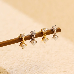 Macro detail of elegant pearl and zircon stud earrings on a wooden display stand