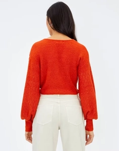 Dettaglio del design incrociato sulla schiena e della trama del maglione arancione