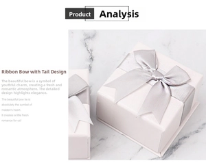 Detail of square jewelry gift boxes with silver ribbon bows on white marble background
