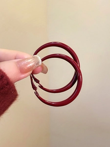 Detail view of large burgundy red glazed hoop earrings with a polished glossy finish