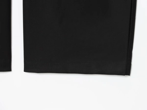 Gros plan détaillé des coutures et de la texture du tissu sur l'ourlet du pantalon noir