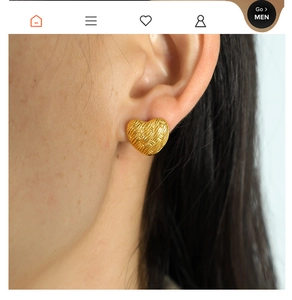 Macro view of gold woven heart earrings on a model's ear showing French vintage style