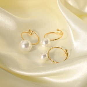 Dreiteiliges Set aus 18K vergoldeten Perlenringen auf elegantem cremefarbenem Seidenstoff
