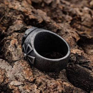 Vintage silver skull and cross relief ring on rustic dark bark with gothic aesthetic