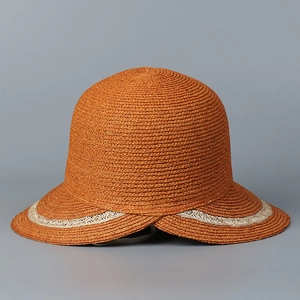 Detail of burnt orange raffia sun hat with cream wavy textured ribbon trim on brim