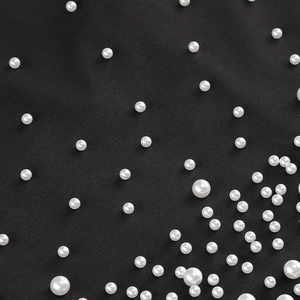 Détail de perles blanches sur tissu noir pour la texture d'une robe de soirée