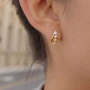 Elegant gold double C-shaped hoop earrings with cubic zirconia stones worn by a model