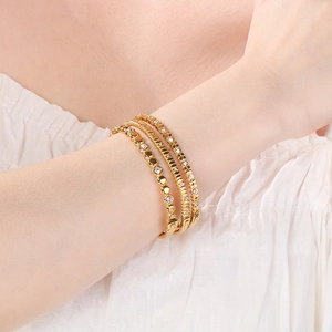 Primo piano di tre eleganti bracciali rigidi in acciaio dorato con cristalli al polso