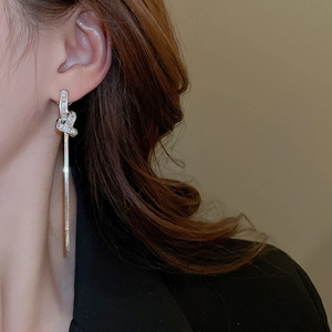 Close-up of silver tassel earrings with knot design and cubic zirconia on model