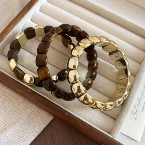 Detail view of amber resin and gold metallic square bead elastic bracelets on jewelry tray